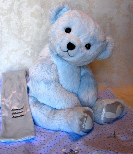 Teddy bear made from blue blanket with footprints.
